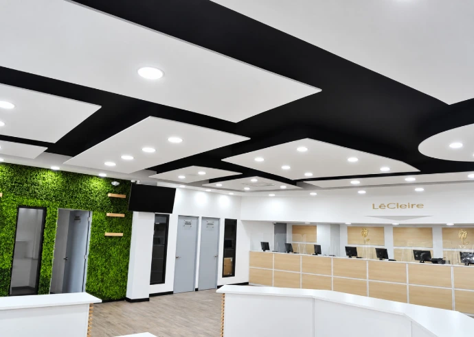 Cielo falso geométrico blanco y negro con iluminación empotrada en recepción comercial.