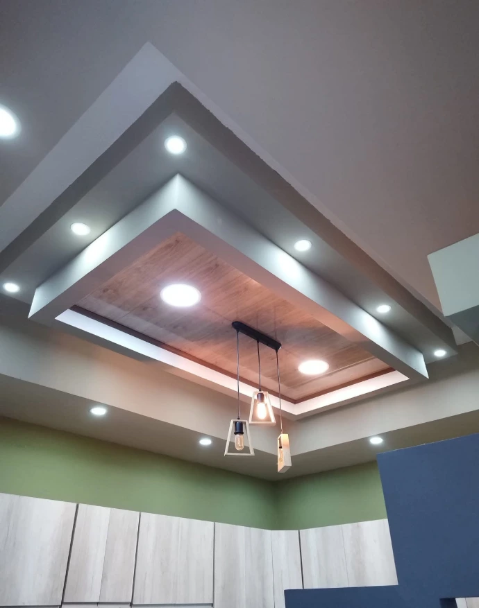 Cielo falso residencial escalonado con iluminación empotrada y lámparas colgantes.