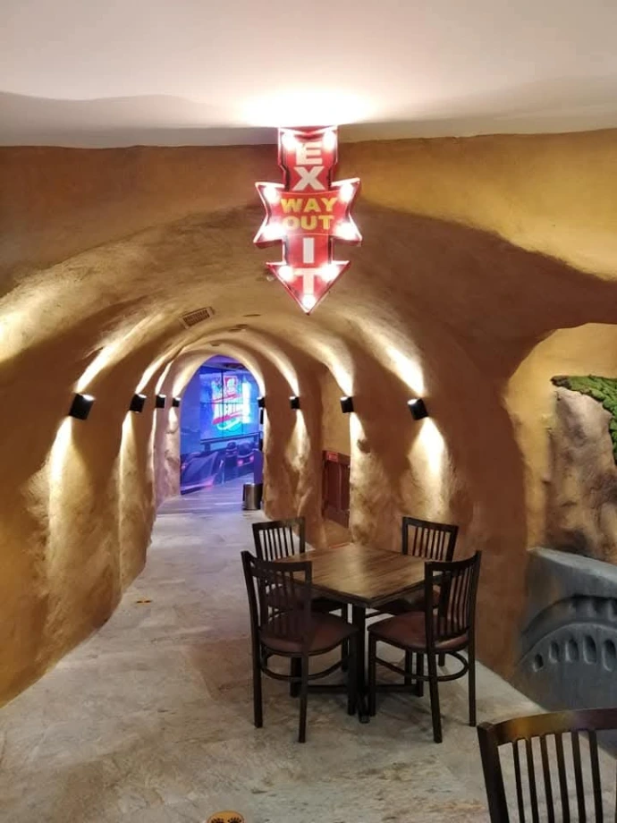 Pasillo temático con formas curvas e iluminación integrada en Pizza Grizzly, Cayalá.