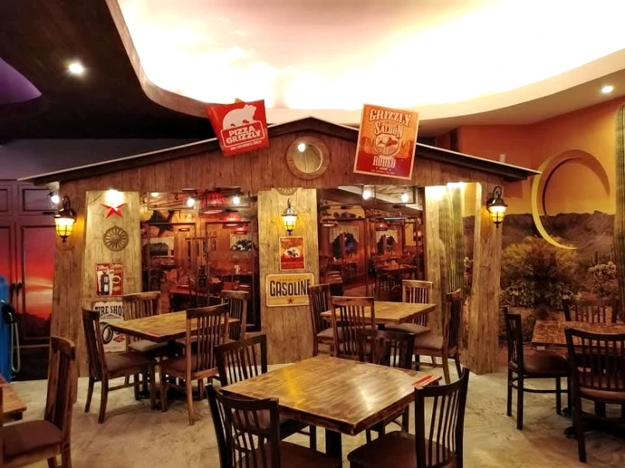Interior de Pizza Grizzly en Cayalá con cielo falso curvo iluminado y ambientación temática.